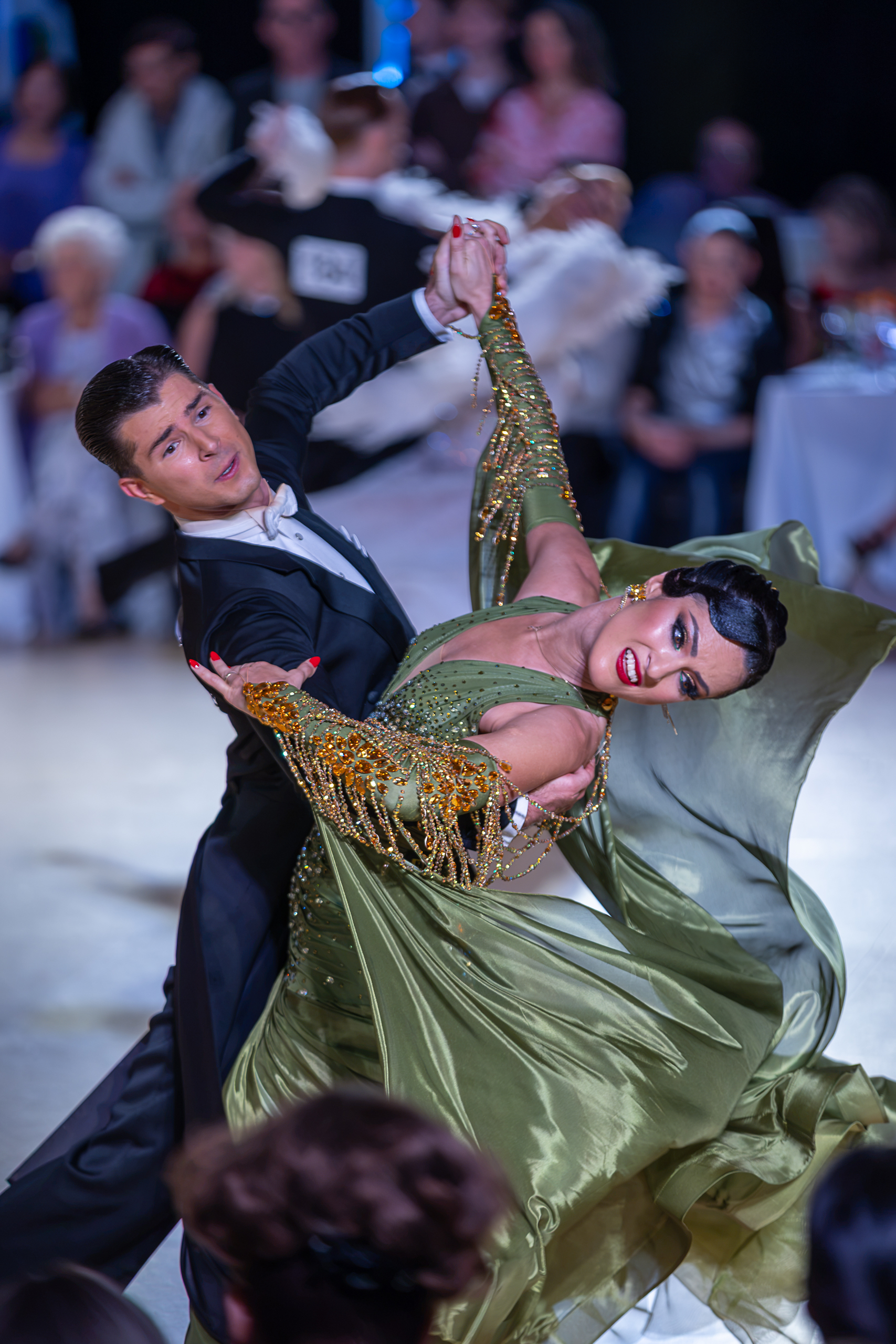 A couple turning together, the dancer’s pale gown billowing across the floor