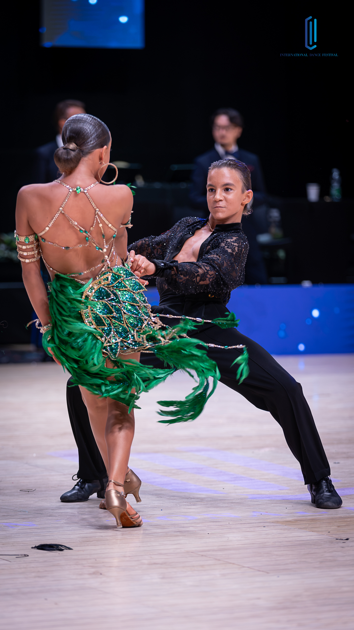 A dancer in a coral gown arching gracefully with her partner