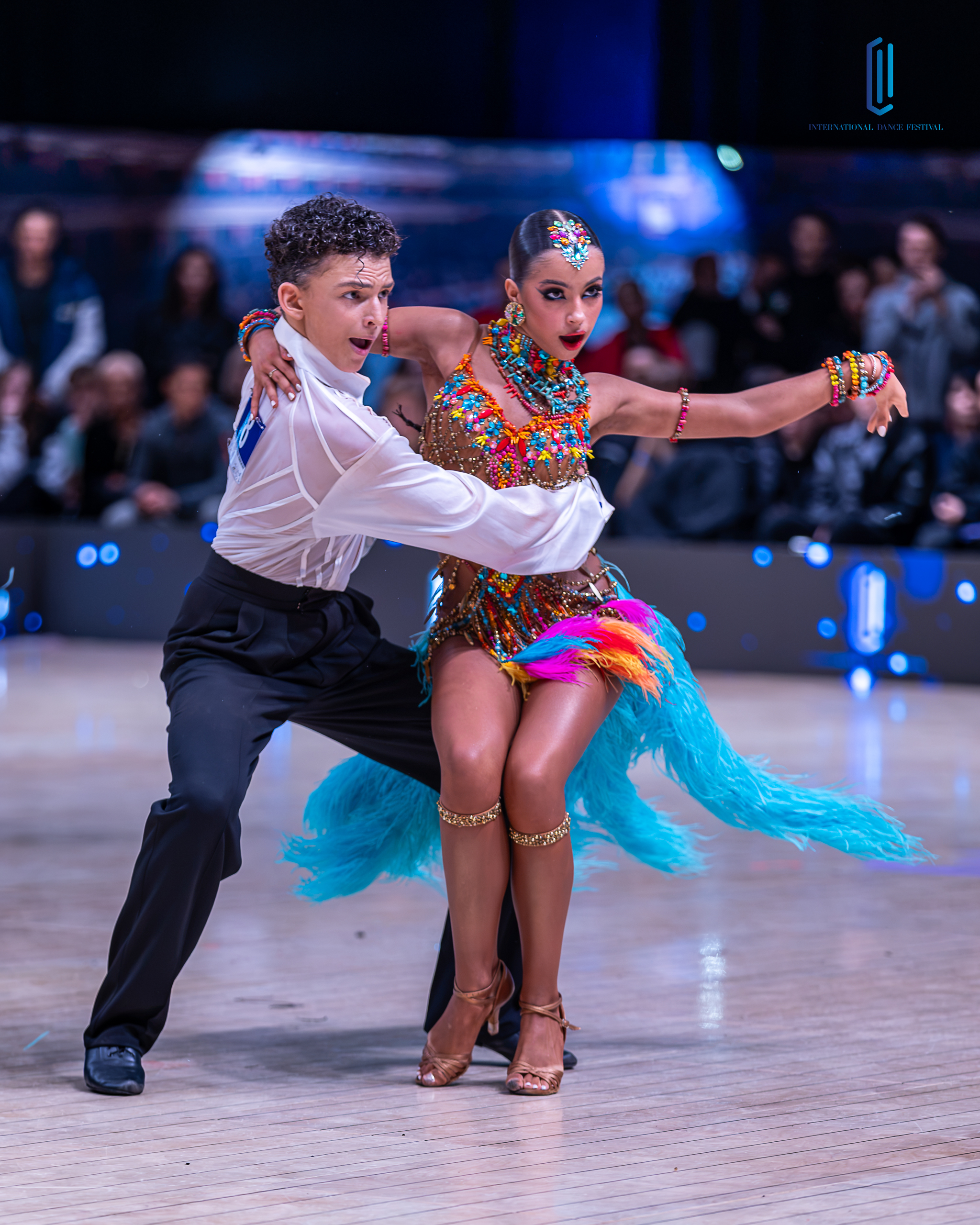 Dancers reaching out across the floor in a flowing coral dress and black tails